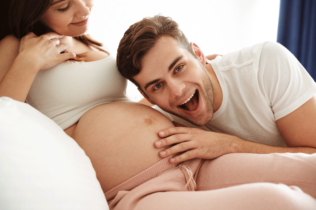 Man happy that he is soon to be a father and he is hugging his pregnant wives belly